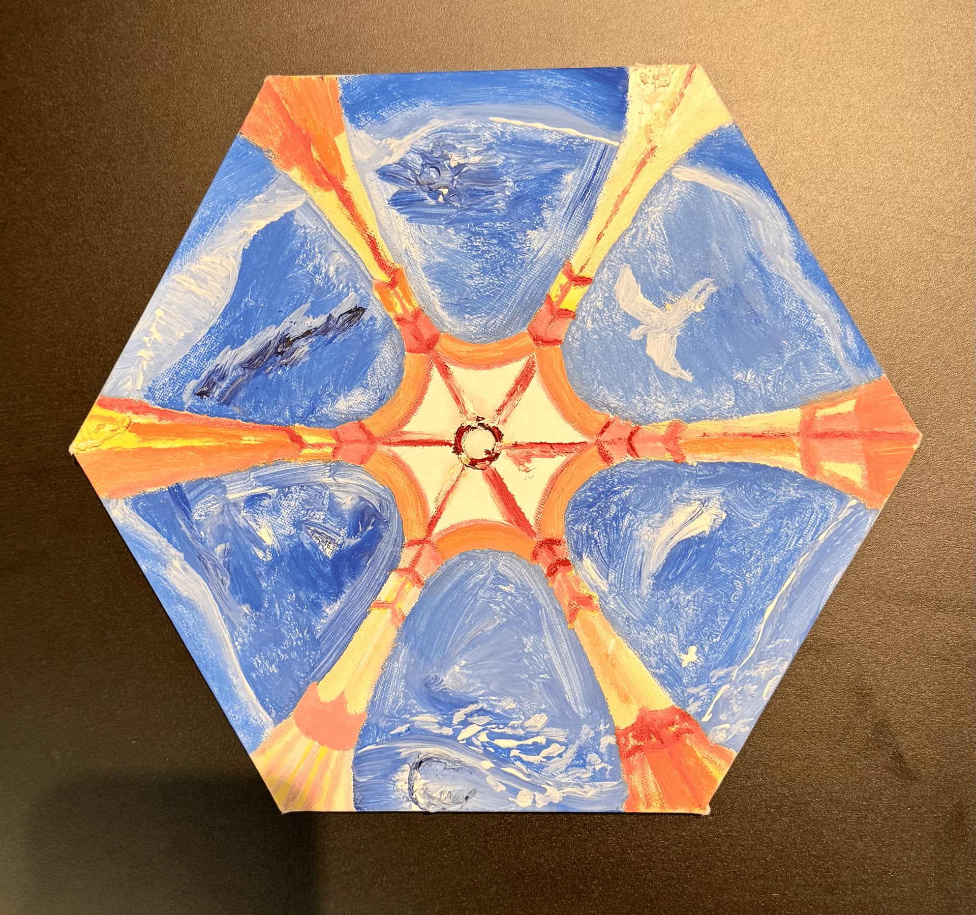 The same hexagonal canvas seen straight on and turned, the white bird now at the right. Six wedges of blue sky meet at a pale centre between ribs of orange, yellow and red.